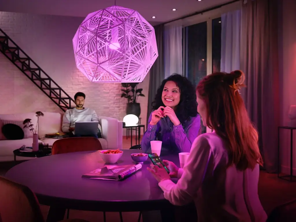 Freunde unterhalten sich im Wohnzimmer mit Philips Hue Color-Ambiance Beleuchtung